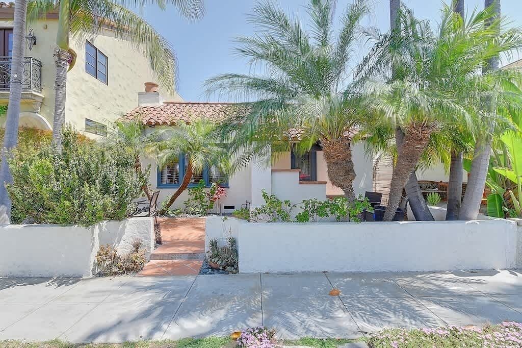 A building with a tiled roof, palm trees, and a pathway leading to a door.