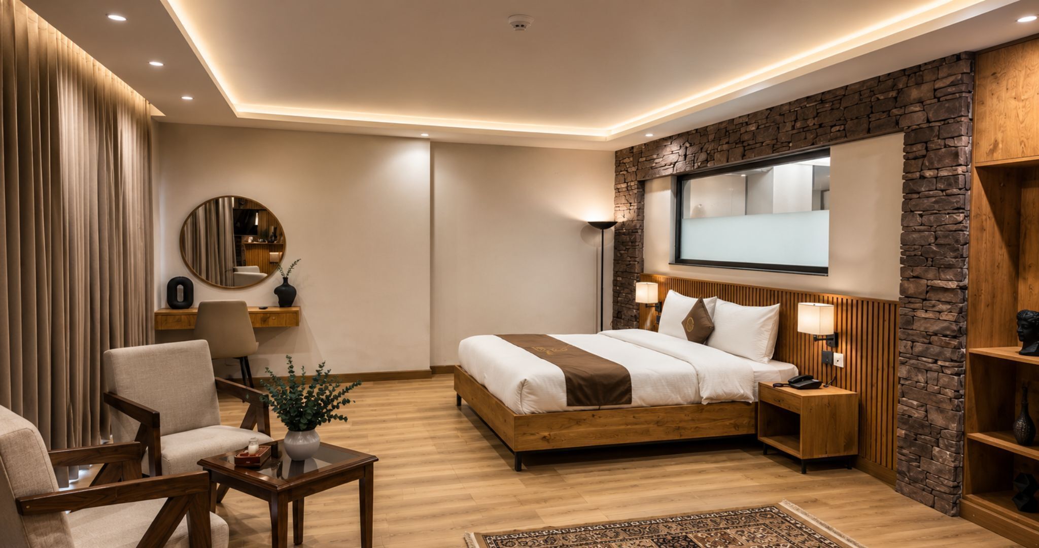 Una habitación de hotel moderna con una cama de madera, un escritorio, una silla, un espejo y una pared decorativa de piedra.