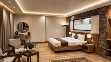 Una habitación de hotel moderna con una cama de madera, un escritorio, una silla, un espejo y una pared decorativa de piedra.