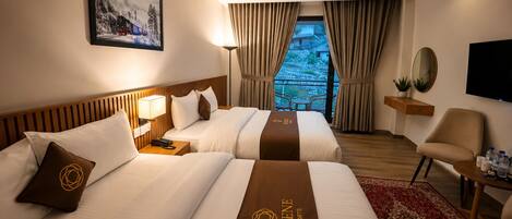 A hotel room with two beds, a TV, a desk, and a view of a mountainous landscape.