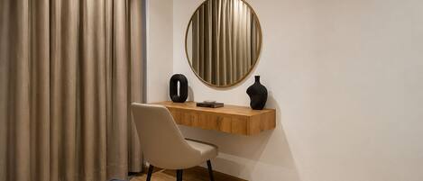 A room with a desk, chair, and a round mirror on the wall.