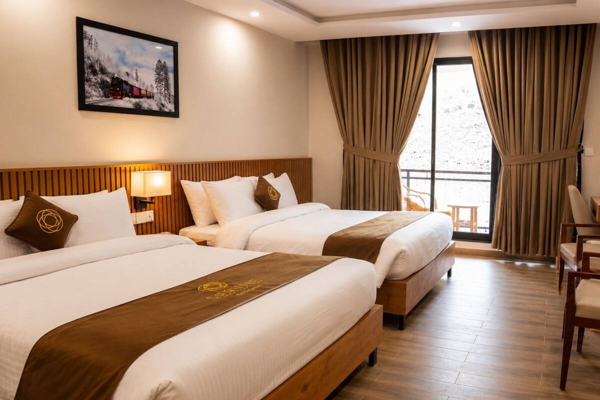 A hotel room with two beds, a TV, a desk, and a window with curtains.