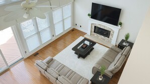 Ein modernes Wohnzimmer mit einer Eckcouch, einem Couchtisch, einem Kamin und einem darüber montierten Fernseher.