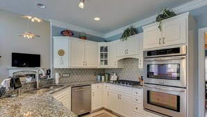 Eine moderne Küche mit weißen Schränken, Edelstahlgeräten, Granitarbeitsplatten und einem eingebauten Backofen.