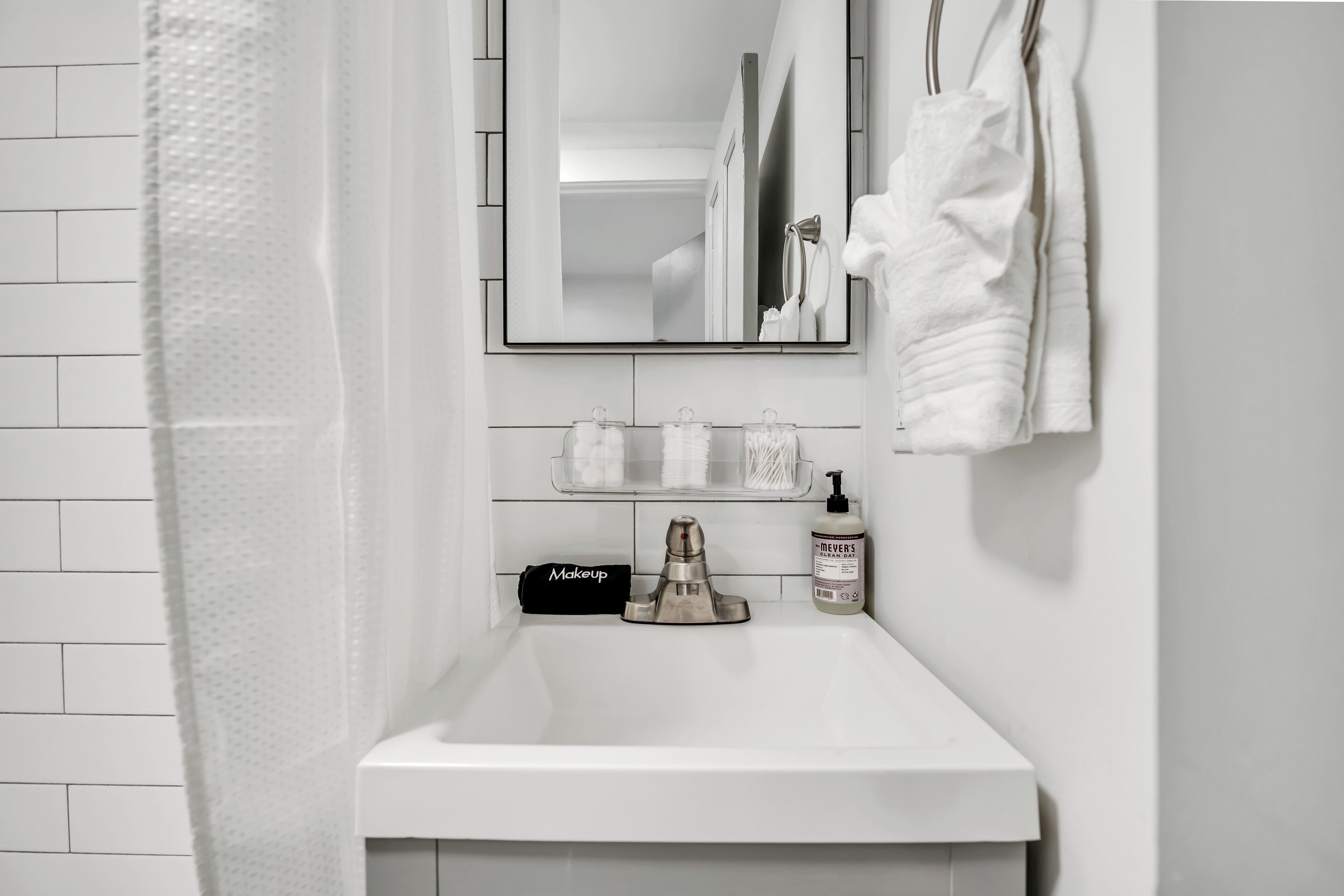 Un bagno con lavandino bianco, uno specchio, portasciuga e articoli da toilette.