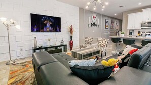 Un salon moderne avec un téléviseur à écran plat, un canapé, une table basse et un fauteuil à motifs.