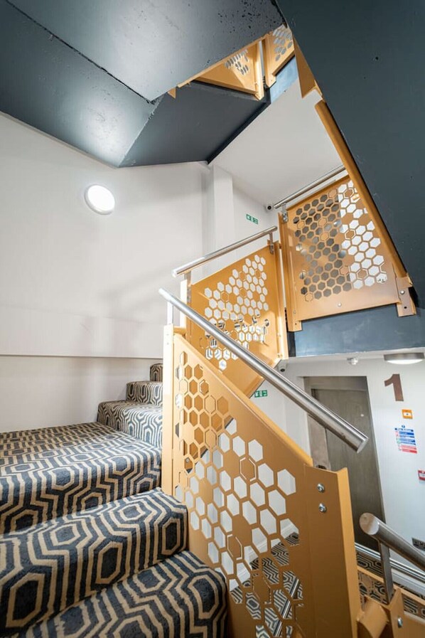 A staircase with a honeycomb pattern railing, a patterned carpet, and a sign indicating room number 1.