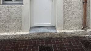 Une porte blanche avec une petite fenêtre au-dessus, le chiffre « 6 » au-dessus de la porte, et une petite marche menant à la porte.