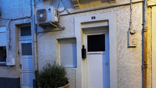 Un bâtiment avec une porte blanche, un pot de fleurs et un appareil de climatisation.