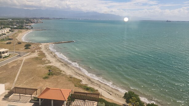 A coastal view with a beach, a pier, and a distant cityscape. - Scenic studio in Portmore, Jamaica (Kingston)