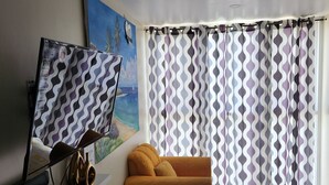A living room with a sofa, a TV, and a painting on the wall. - Scenic studio in Portmore, Jamaica (Kingston)