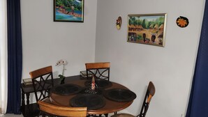 A dining area with a round table, six chairs, and a chandelier.