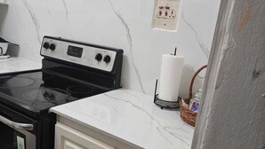 A kitchen with white marble countertops, a black stove, and white cabinets.