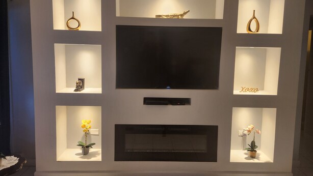 A modern living room with a large flat-screen TV centered above a fireplace.