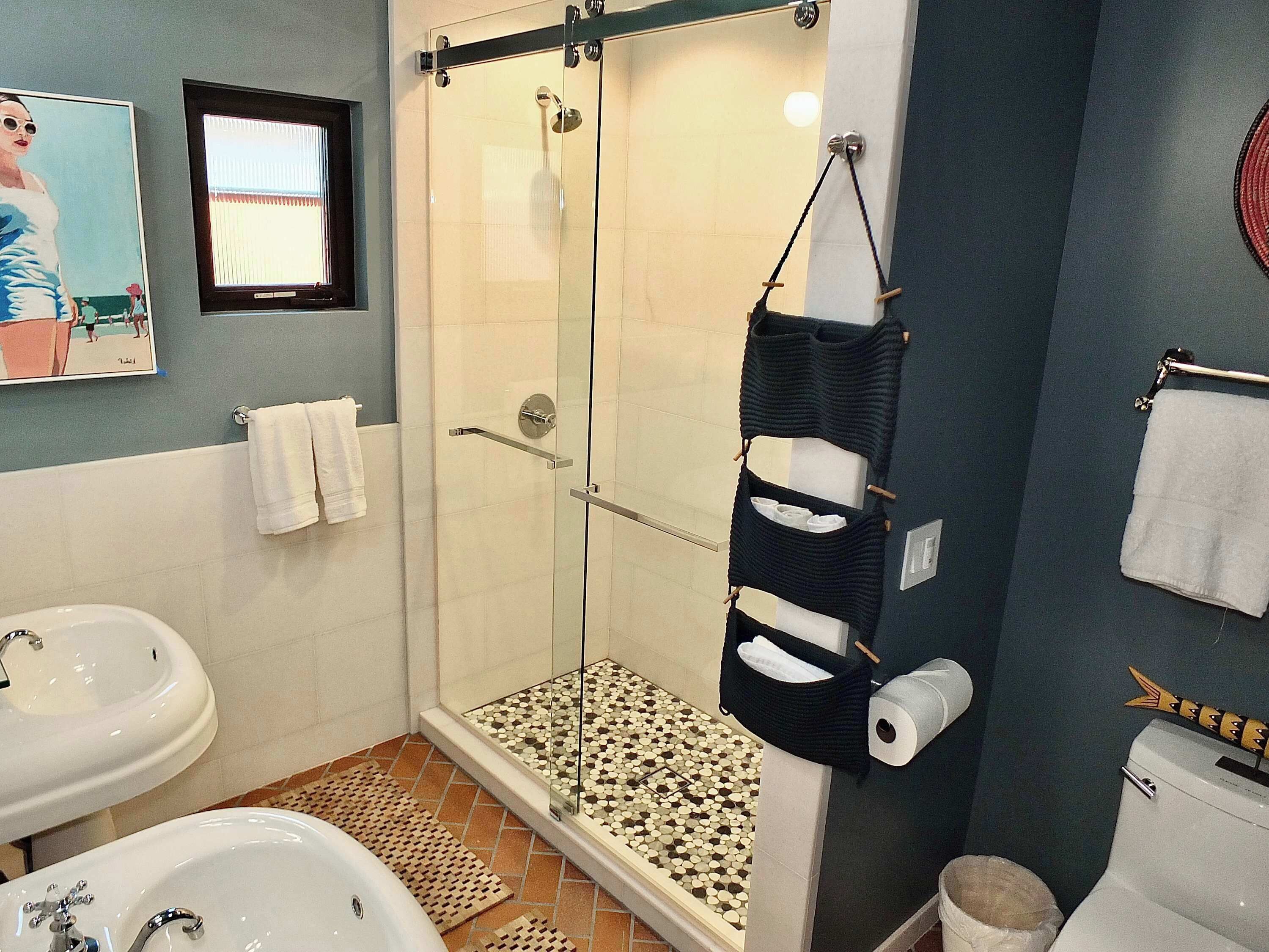 A bathroom with a glass-enclosed shower, a sink, a toilet, and a towel rack.