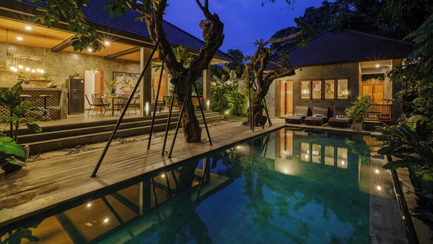 A pool area with a wooden deck, lounge chairs, and a dining area with a table and chairs. - Villa Gaya Ubud (Ubud)