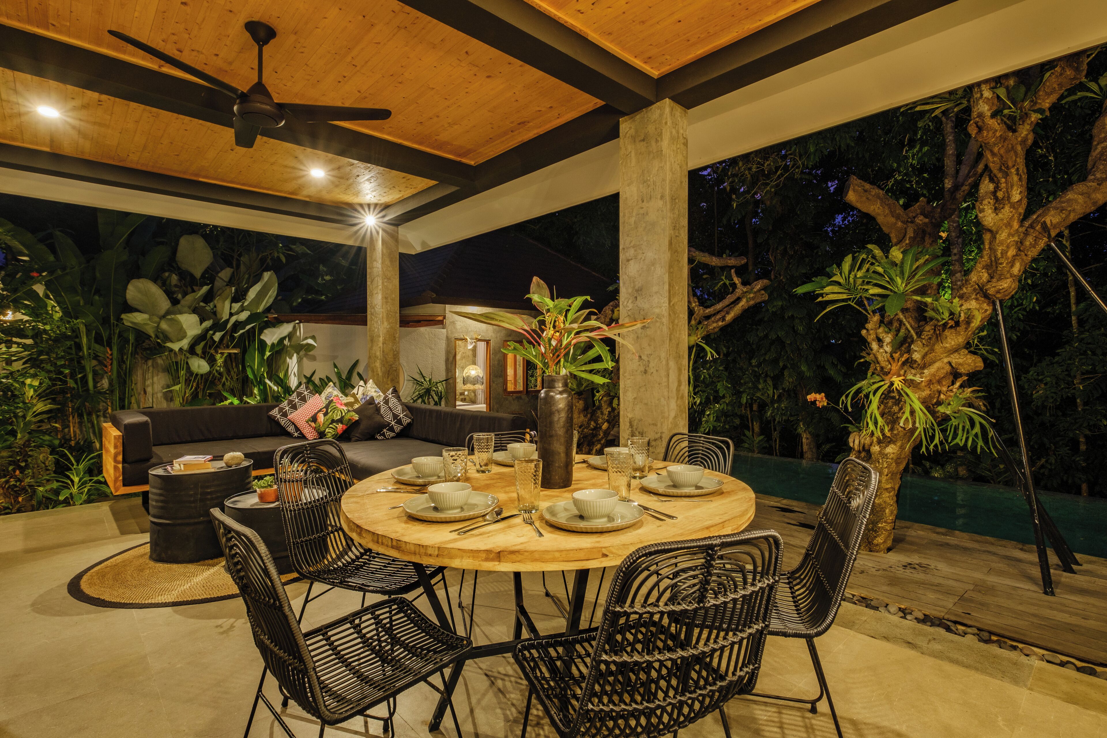An outdoor dining area with a round table, chairs, and a ceiling fan.