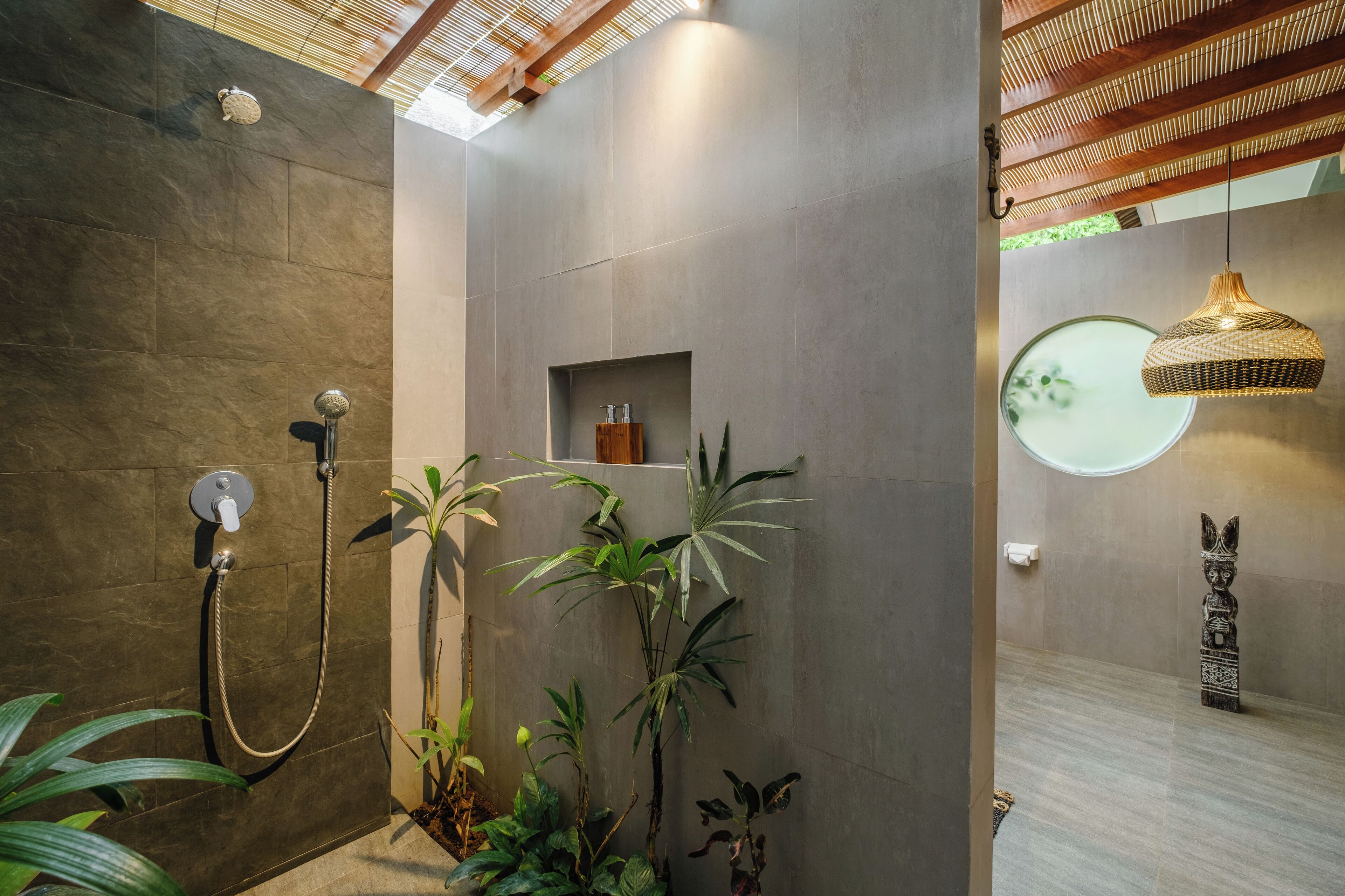 Ein modernes Badezimmer mit Dusche, Ablage für Toilettenartikel und einer Pendelleuchte.