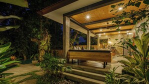 A modern outdoor patio with a wooden bench, stone pathway, and lush greenery. - Villa Gaya Ubud (Ubud)