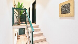 A staircase with a glass railing, a potted plant, and a piece of abstract art on the wall.