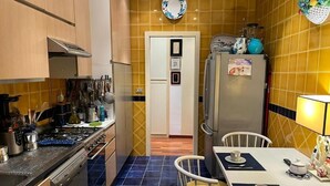 A compact kitchen with a stove, sink, and refrigerator. A dining table with chairs is positioned in front of the kitchen. - Charming bed & breakfast in enchanting Roma with AC and WiFi. (Roma)