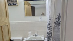 Een badkamer met toilet, wastafel en spiegel.