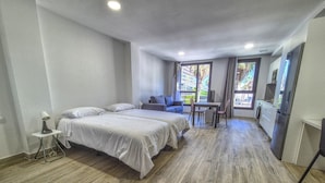 Une chambre d’hôtel moderne équipée de deux lits, d’une petite table à manger, d’un canapé et d’un coin cuisine.