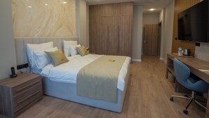 Una habitación de hotel moderna con una cama grande, un escritorio y un televisor.
