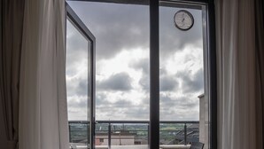 Un balcón con mesa y sillas, un reloj y vistas a la ciudad.