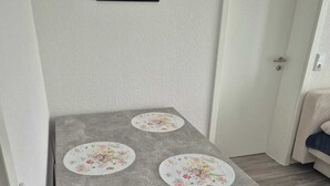 Une petite table carrée, avec un plateau en pierre grise et des sets de table à motifs floraux.
