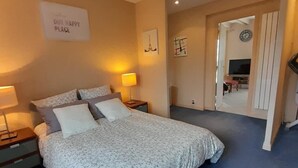 Un dormitorio con una cama, dos mesitas de noche con lámparas, un reloj de pared y un cartel que dice 'OUR HAPPY PLACE'.