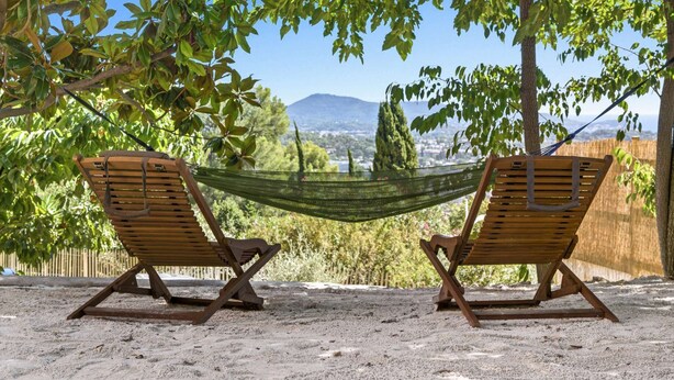 Two wooden lounge chairs under a hammock, set on a sandy ground with a view of a distant town and mountains. - Panoramic sea view villa & heated pool (Toulon)