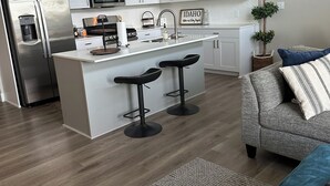 Une cuisine moderne dotée d’un îlot central, de tabourets de bar, d’un réfrigérateur et d’un four à micro-ondes.