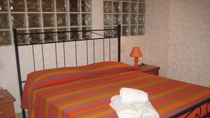 Una cama con un edredón a rayas y una toalla doblada.