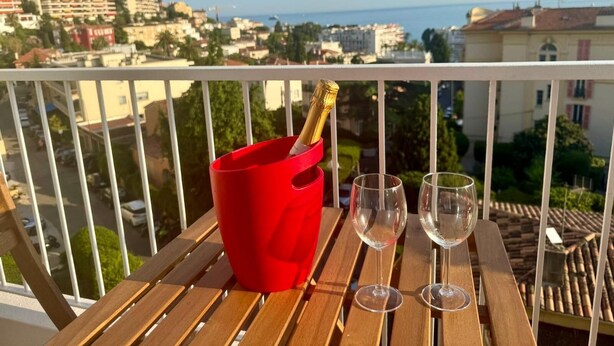 A balcony with a wooden table, a red bucket, and two empty wine glasses. - SEASIDE Apartement, Calm, chill, Nice (Nice)