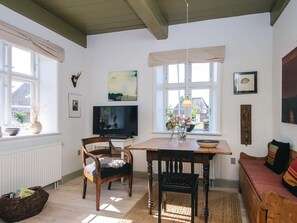 A cozy living room with a wooden table, two chairs, a television, and a sofa. - 4 Person Holiday Home in Hojer (Højer)