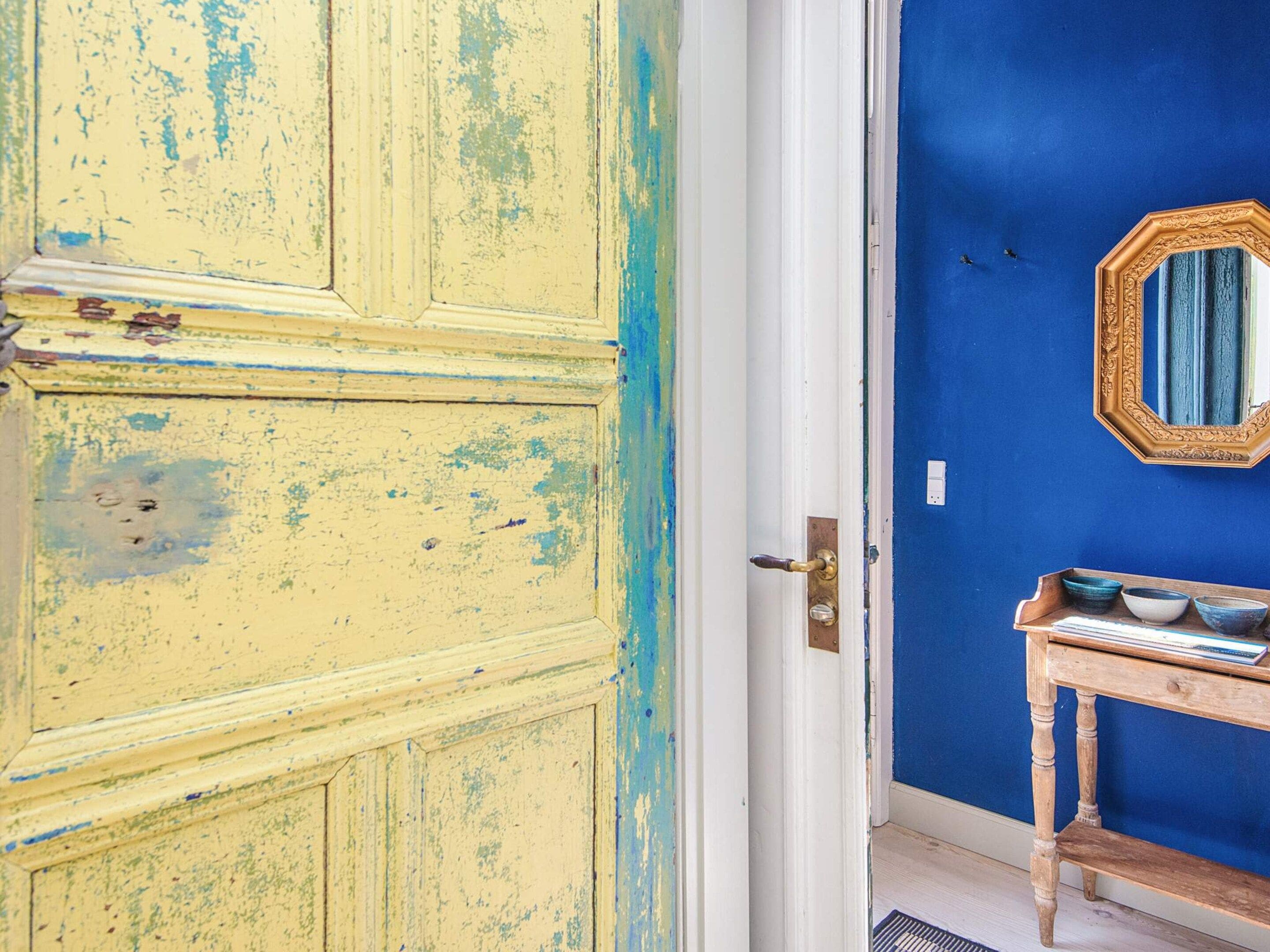 Una habitación con una puerta amarilla, una pared azul y una mesita de madera con cuencos.