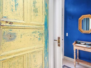 A room with a yellow door, a blue wall, and a wooden side table with bowls.