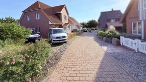 A residential street with houses, a driveway, and a parked van. - Spacious, bright vacation home within walking distance of only 500m to the beach, with beautiful garden (Dassow)