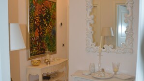 Ein Badezimmer mit einem weißen Waschtisch, einem großen Spiegel und einem farbenfrohen Bild an der Wand.