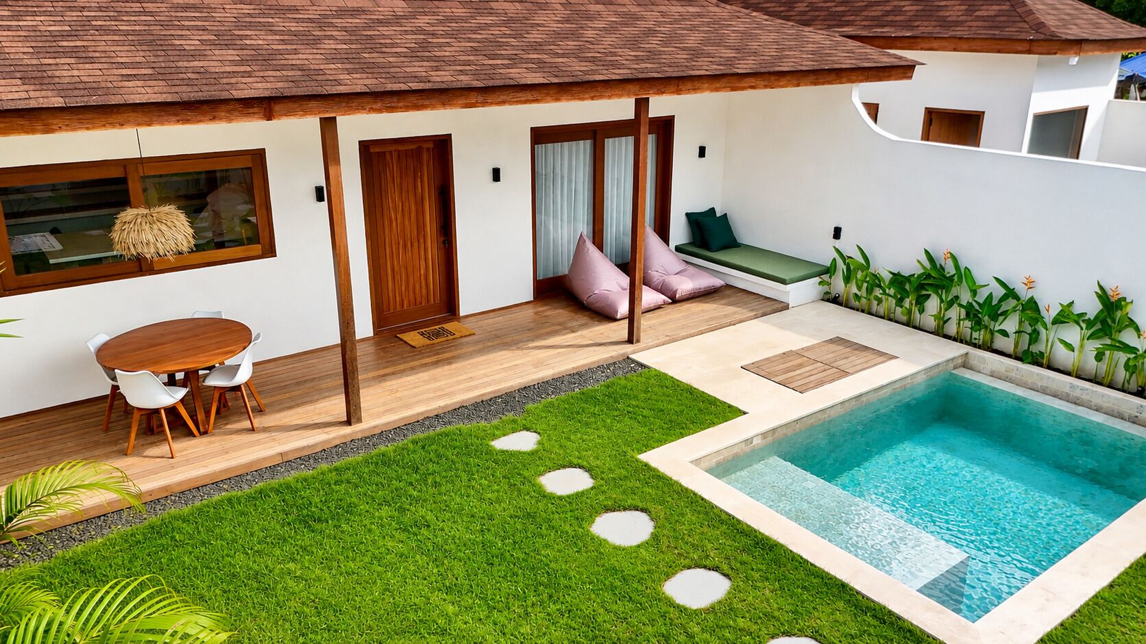 Una casa moderna con piscina, un patio con mesa y sillas, y un césped bien cuidado.