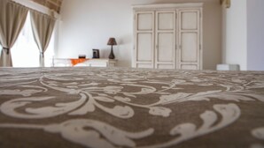 Una habitación con alfombra estampada, un armario blanco y una lámpara sobre una mesita de noche.