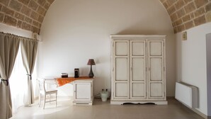 Una habitación con un escritorio blanco, una silla, un armario y un radiador.