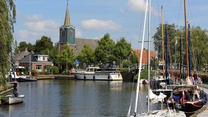 En kanal med båtar, en kyrka och ett bostadsområde.