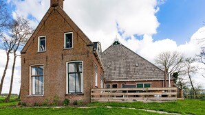 Ett traditionellt hus byggt av tegel med ett brant gavelformigt tak, stora fönster och en träveranda.