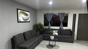 A modern living room with a grey sectional sofa, a small round table, and a potted plant.