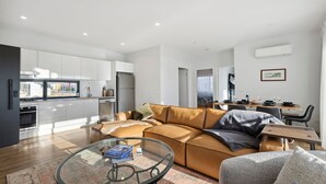 A modern apartment with a living area, kitchen, dining space, and a view of the outside. - The Crystal Palace 2, pet friendly 2 bedroom apartment (Jindabyne)