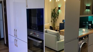 A modern kitchen with built-in appliances, a dining area with a sofa, and a large mirror.