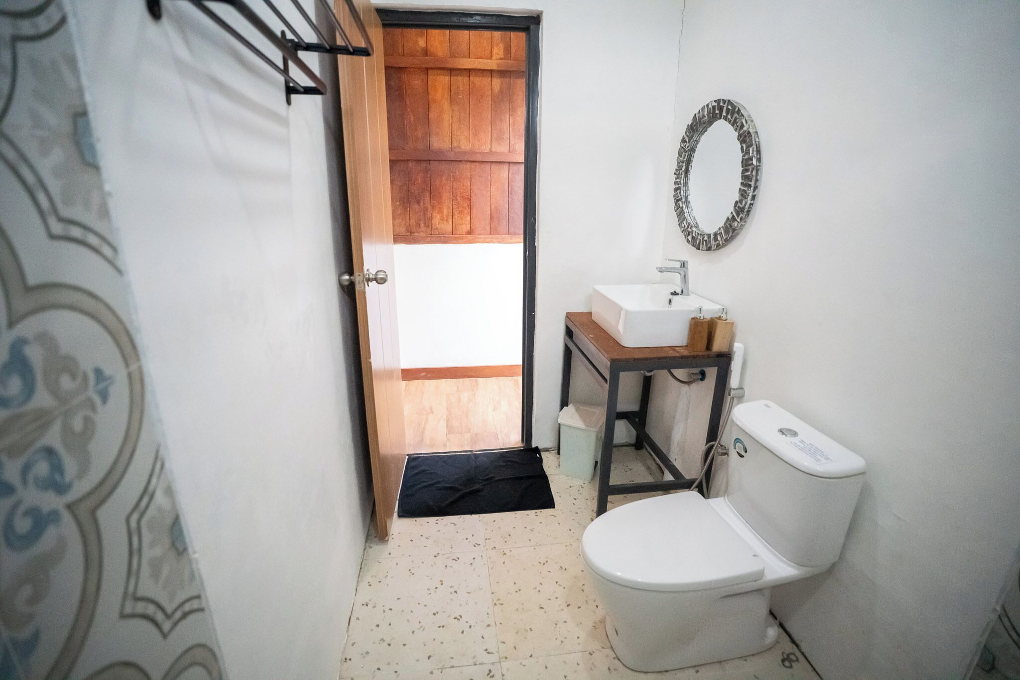 A small bathroom with a wooden door, a white sink, a mirror, and a toilet.