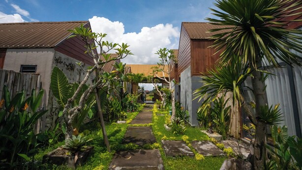 A narrow pathway flanked by wooden structures with tropical plants. - Kose Villa Ubud (Ubud)